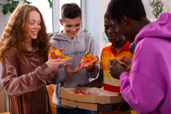 Čtyři Teenageři jedí pizzu po studiu — Stock fotografie