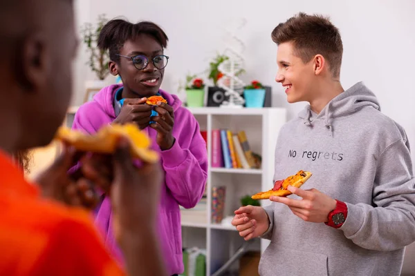 Tieners dragen stijlvolle Hoodies praten en eten pizza — Stockfoto