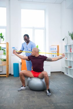 Sporcu ile çalışırken gülümseyen fizyoterapist