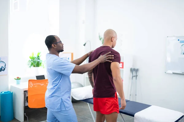 Gevilde sporttherapeut staande in de buurt van zijn bezoeker — Stockfoto