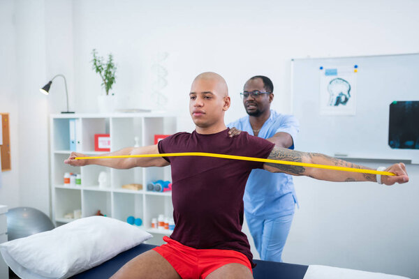 Культурист делает упражнения во время посещения физиотерапевта
