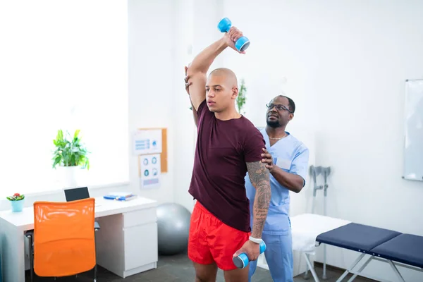 Sportsman gazdaság barbells látogatása közben fizikai terapeuta — Stock Fotó