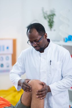 Erkek diz muayene koyu tenli terapist yakın çekim