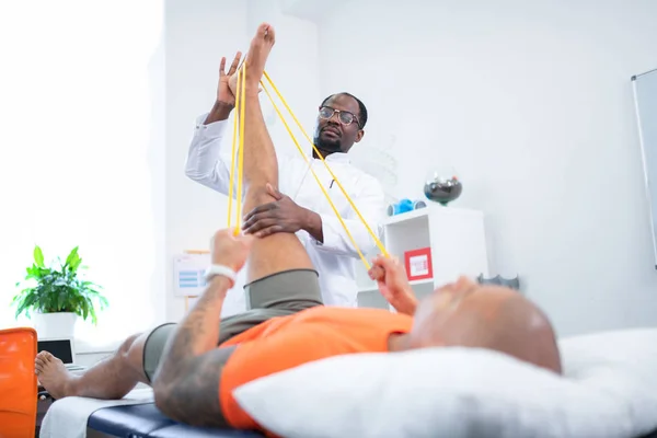 Терапевт допомагає пацієнту розтягувати ногу після тренування — стокове фото