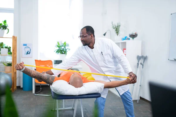 Темношкірий терапевт торкається татуйованої руки спортсмена — стокове фото