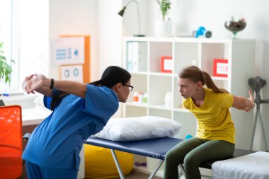 Özenli bakım uzun saçlı doktor küçük kızın duruş düzeltme