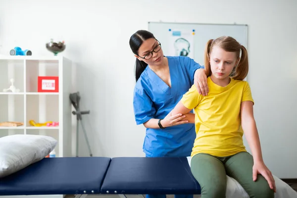 Ongemakkelijk jong meisje waardoor donkerharige verpleegster bewegen haar hand — Stockfoto