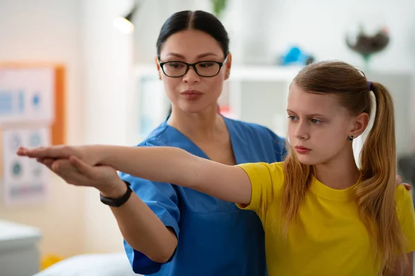 Supportive beaming dark-haired doctor gently holding her young patient — Stock Photo, Image