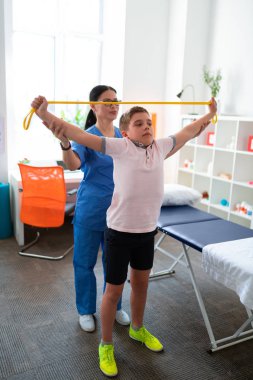 Ciddi küçük çocuk sarı ip ile ellerini yükselterek