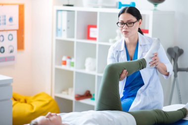 Doğru profesyonel hemşire küçük kızın sorunlu bacak hareketli