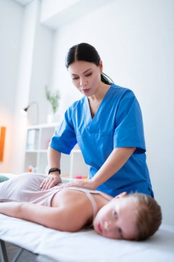 Küçük çocuk ile ilgili mavi üniformalı özenli koyu saçlı kadın