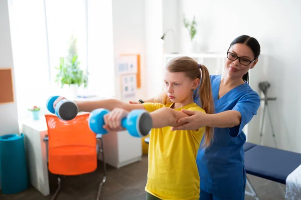 Enfermera morena positiva de apoyo tocando a la niña durante la cita — Foto de Stock