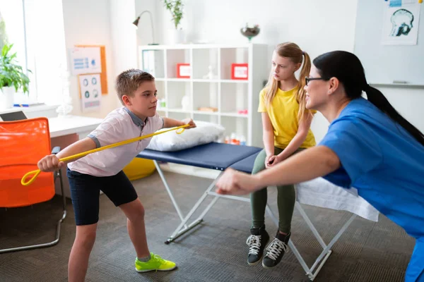 Terapeuta professionista in uniforme blu che lavora con i bambini piccoli — Foto Stock