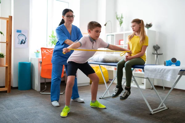 Skicklig långhårig rehabiliterings specialist som visar rätt hållning — Stockfoto