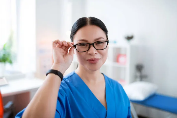 Dobře vypadající asijský doktor se dotkl jejích jasných brýlí — Stock fotografie