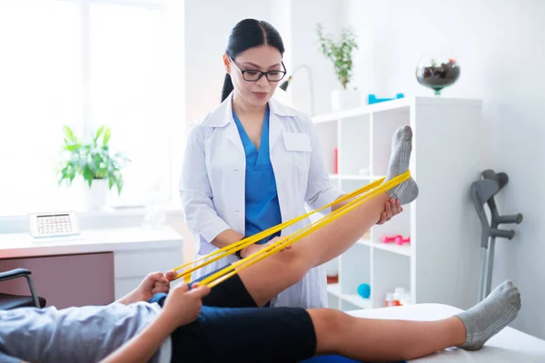 Gericht donkerharige therapeut inspecterende staat van het been — Stockfoto