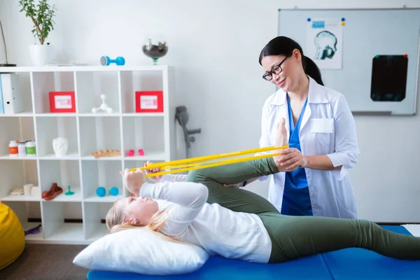 Stralende prettige dame die haar schattige jonge patiënt helpt — Stockfoto