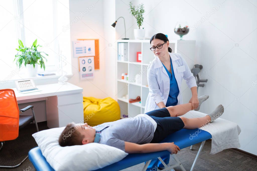 Gentle professional doctor moving around hurting leg