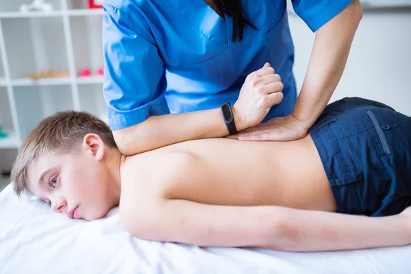 Mestre de massagem forte em camisa azul pressionando intensamente as costas — Fotografia de Stock