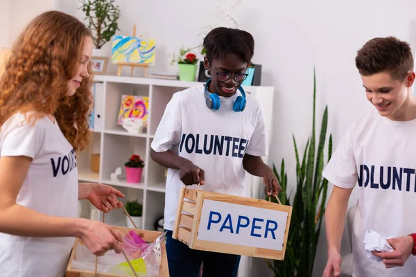 Dark-skinned teenager in glasses holding box with paper — Stock Photo, Image