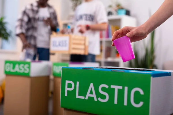 Chica poniendo plástico en la caja de clasificación de basura en la organización de la ecología —  Fotos de Stock