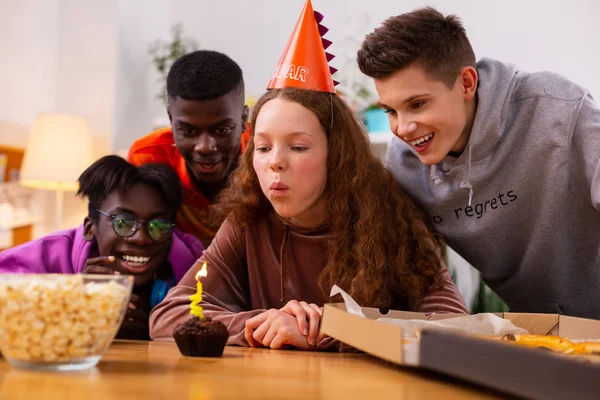 Chica pidiendo un deseo sentado cerca de pequeño panecillo de cumpleaños con vela — Foto de Stock