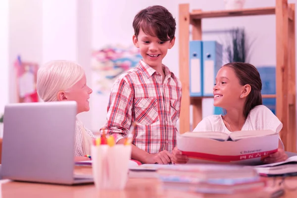 Drei Schulkinder lächeln einander an, während sie Chinesisch lernen. — Stockfoto