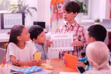 Okul çocuğu arkadaşlarına yeni bir zaman çizelgesi gösteriyor.