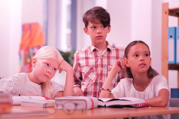 Tres alumnos confundidos escuchando a su profesor . — Foto de Stock