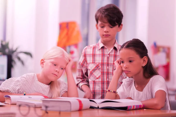 Tres alumnos sentados tristemente en el escritorio . — Foto de Stock