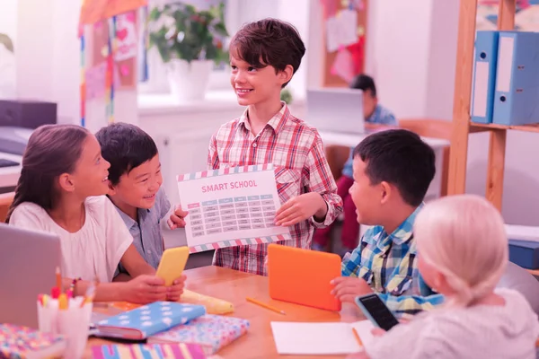 Sonriente niño de pie con horario delante de sus amigos . —  Fotos de Stock