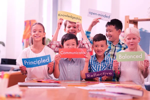 Kinderen van verschillende rassen houden kleurrijke bijvoeglijke naamwoorden. — Stockfoto