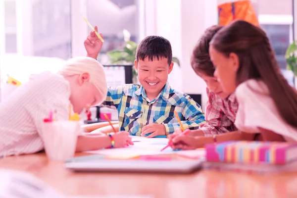 Smiling boy sitting among his drawing friends. — Stock Photo, Image