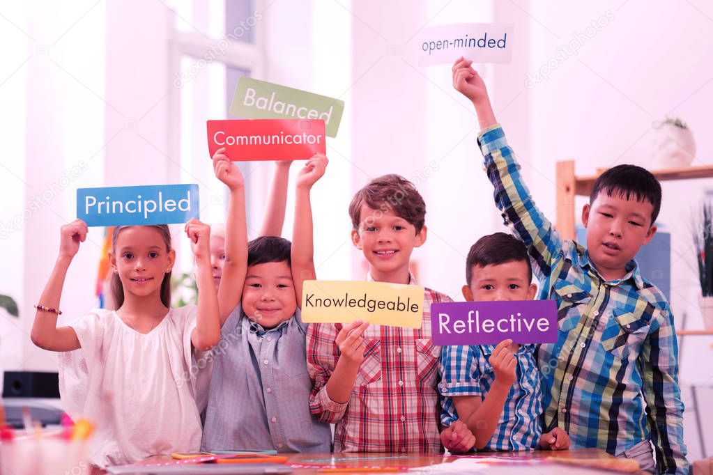 Children holding up sheets of paper with English words.