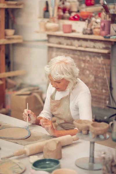 Mujer envejecida creativa usando un pincel para pintar —  Fotos de Stock