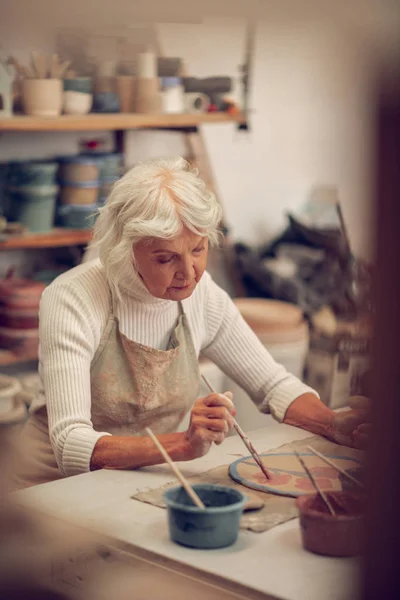 Agradable mujer de pelo gris que trabaja sola en el taller — Foto de Stock