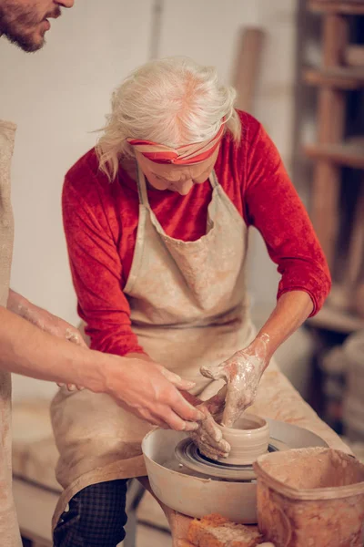 Mujer seria anciana mirando la rueda de cerámica —  Fotos de Stock