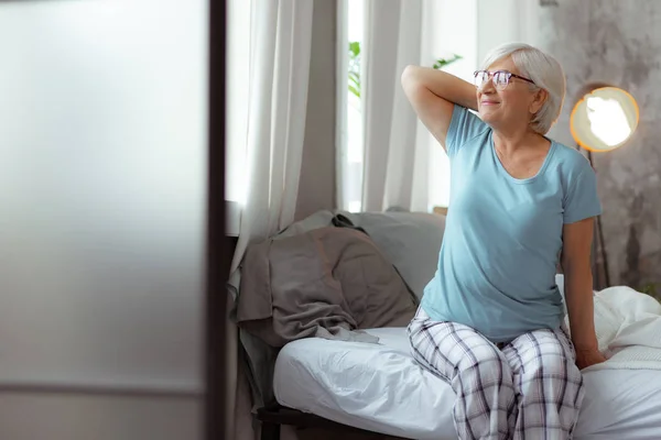 Schön aussehende Frau, die im Bett ins Fenster schaut. — Stockfoto