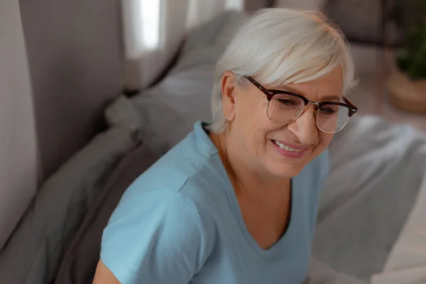 Face-porträtt av rynkig kvinna som bär glasögon och ljusblå t-shirt — Stockfoto