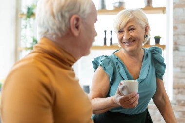 Bir fincan tutarken hoş bir kadın sevgiyle kocası bakıyor