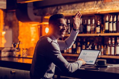 Freelancer arkadaşı sallayarak dizüstü bilgisayar ile bar standında oturan