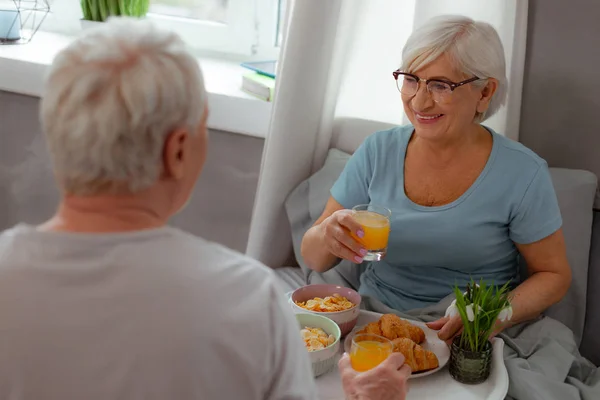 Brillante moglie avendo succo di frutta e cereali colazione con il coniuge — Foto Stock