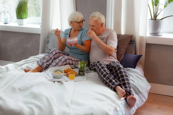 Gloeiende vrouw het eten van granen terwijl haar man het drinken van jus d'orange — Stockfoto
