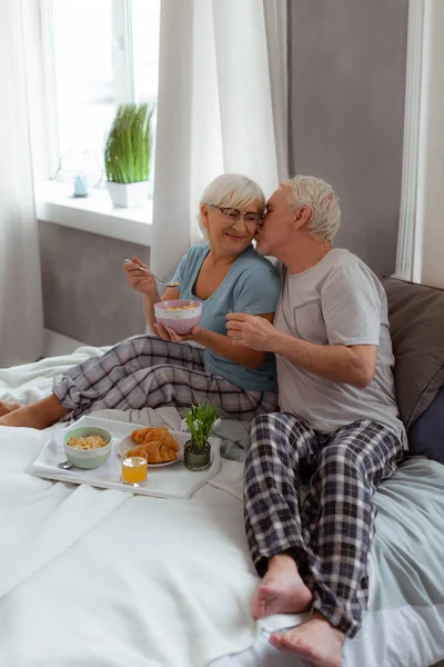 Liebender Ehepartner küsst seine Frau beim Frühstück im Bett — Stockfoto