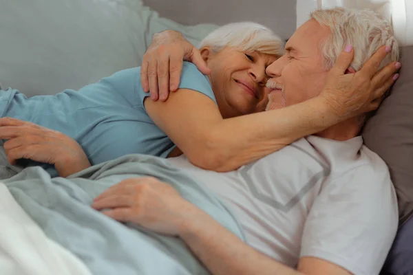 Liefdevolle vrouw teder knuffelen haar echtgenoot terwijl liggend met hem — Stockfoto