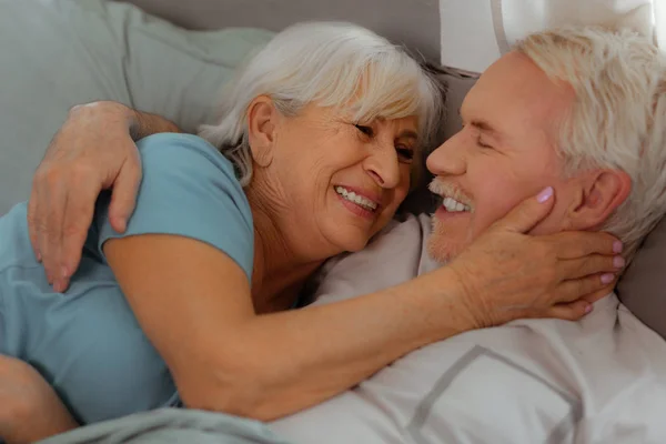 Primer plano de los esposos abrazándose y acostándose en la cama . — Foto de Stock