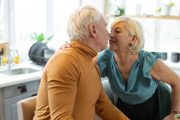 Feliz seductor envejecimiento cónyuge tiernamente besar su envejecido gris-pelo marido . — Foto de Stock