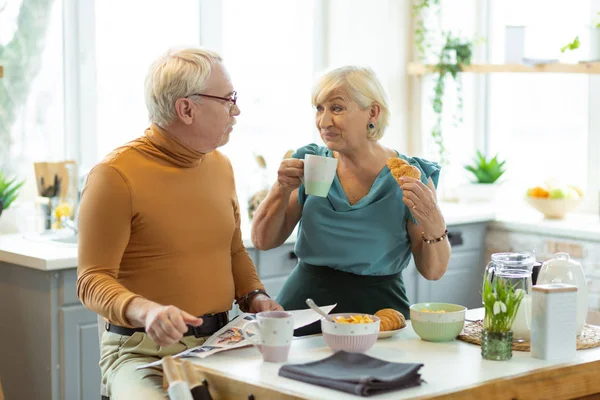 Casal alegre tomando café da manhã e conversando na mesa da cozinha — Fotografia de Stock