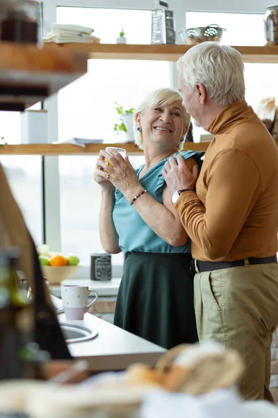 Щасливий чоловік і дружина обіймають один одного на кухні — стокове фото