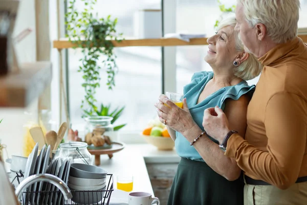 Портрет мужчины, обнимающего свою пожилую жену на кухне . — стоковое фото